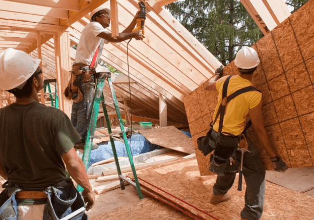 A group of men working on the roof of a house.